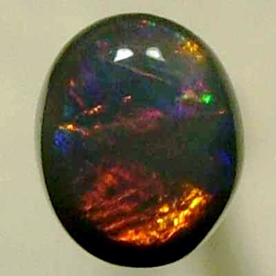 SOLID BLACK OPAL Rolling flashes of bright reds contrast with peacock blue
