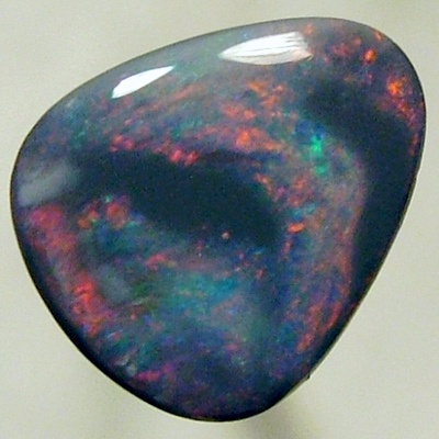 SOLID BLACK OPAL Black opal surrounded by sparkles of red on a green background