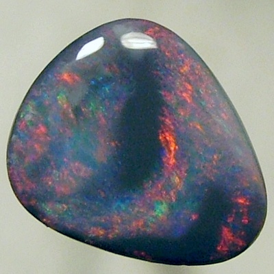 SOLID BLACK OPAL Black opal surrounded by sparkles of red on a green background